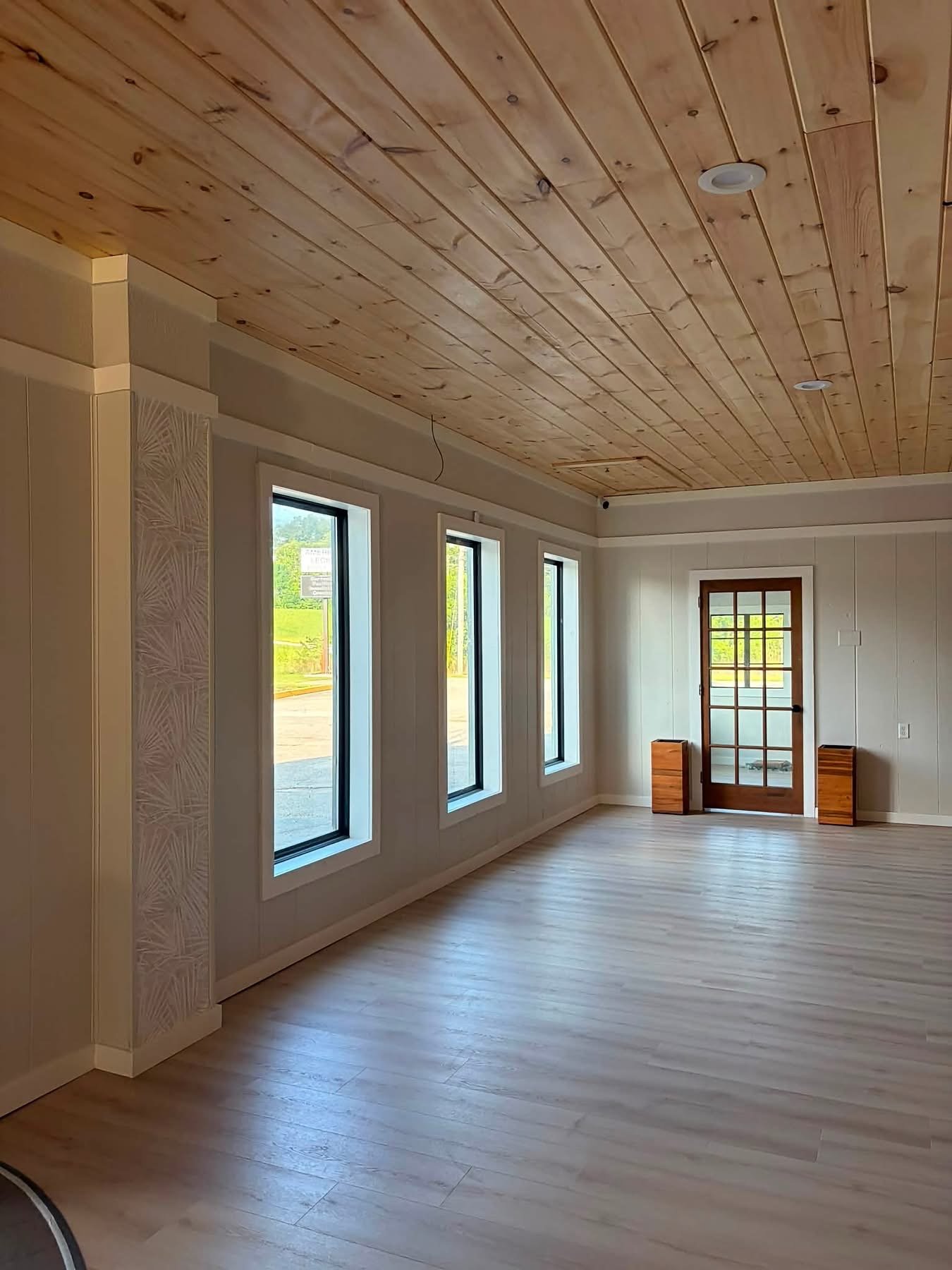 Event room at MeetUps Event Center with natural light, warm wood ceiling, and guest entry view
