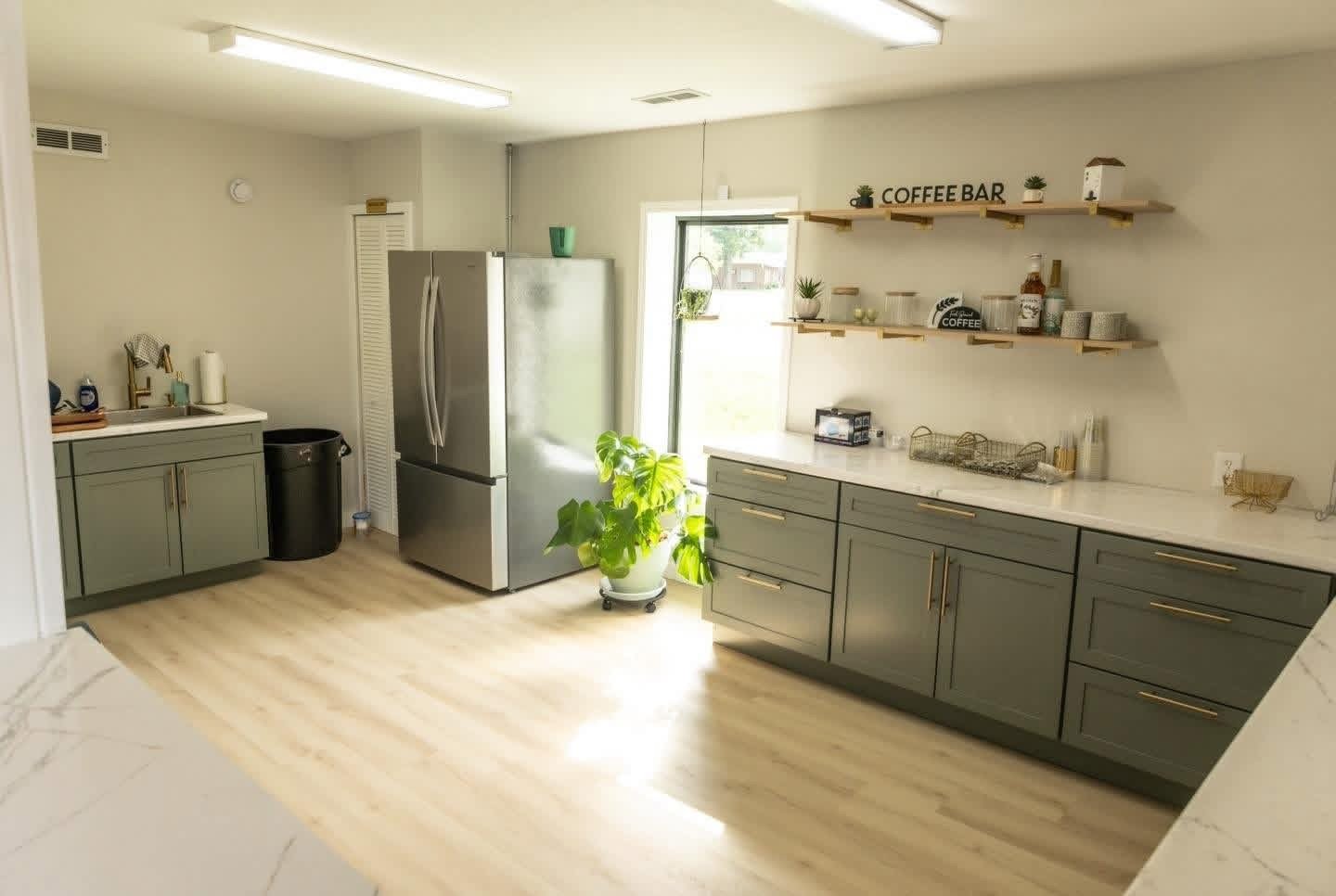Bright kitchen support area with coffee bar shelving, refrigerator, and countertop workspace at MeetUps Event Center